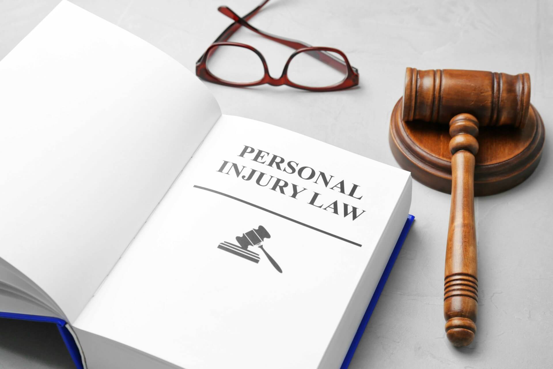 Open book titled 'Personal Injury Law' next to a gavel and eyeglasses.