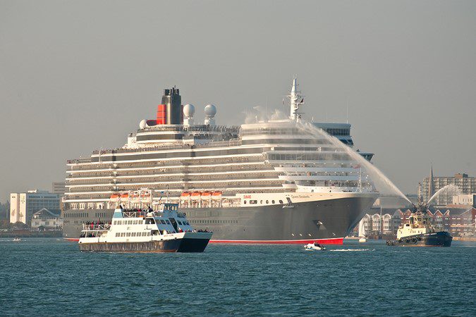 Large cruise ship in a harbor with smaller boats nearby.